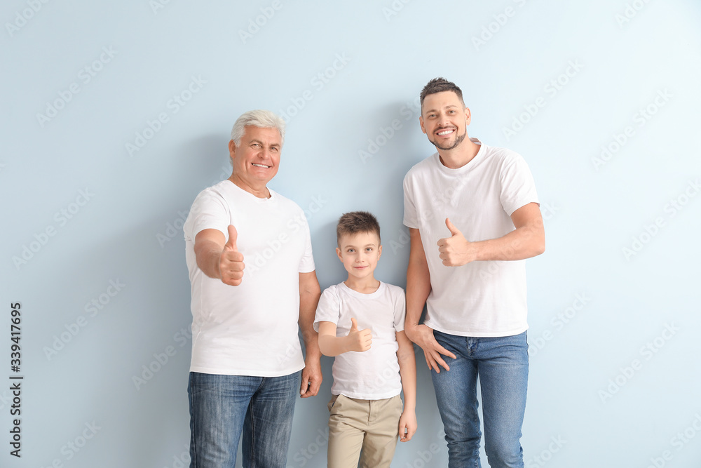 Man with his father and son showing thumb-up gesture on color background