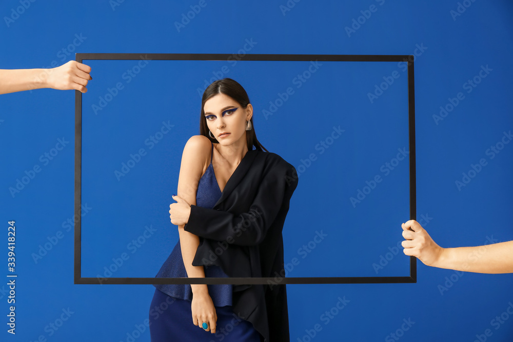 Portrait of fashionable young woman on blue background