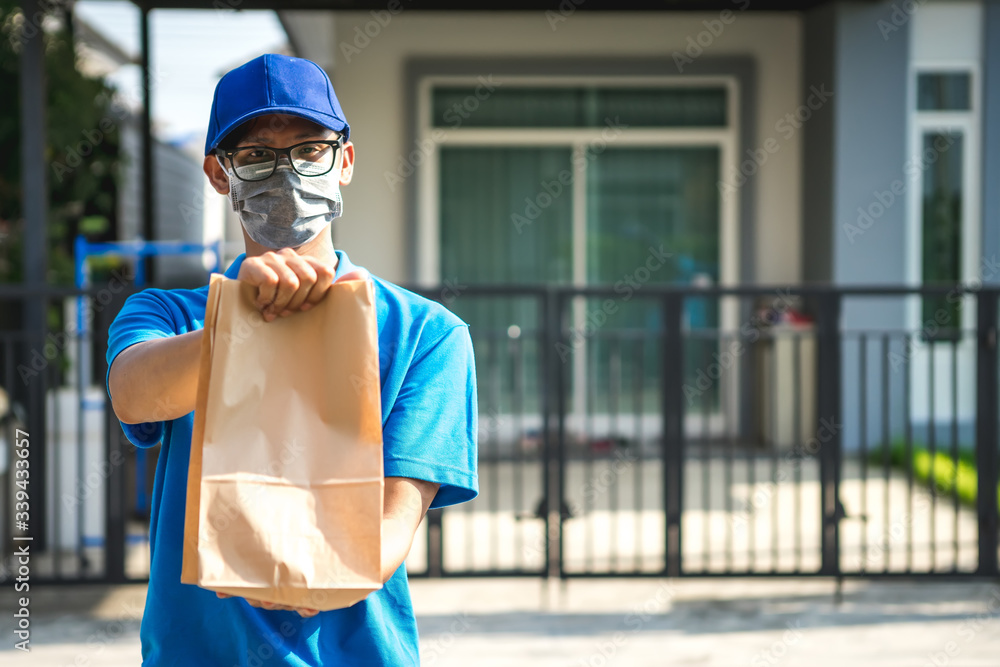 Asian delivery man wearing mask delivers parcel, customer in medical gloves signs on tablet. Deliver