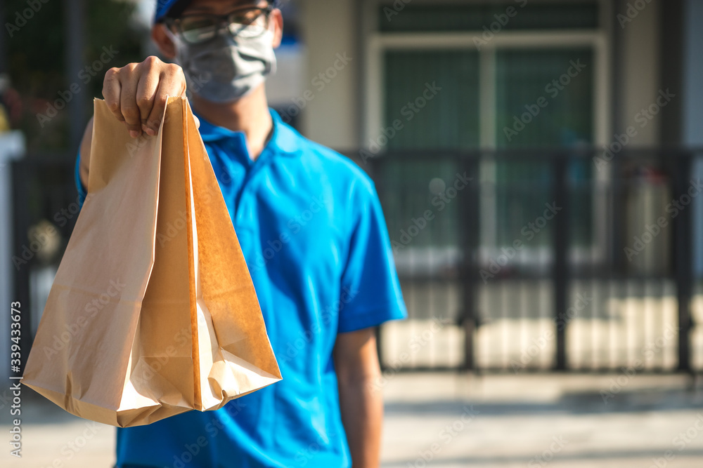 Asian delivery man wearing mask delivers parcel, customer in medical gloves signs on tablet. Deliver