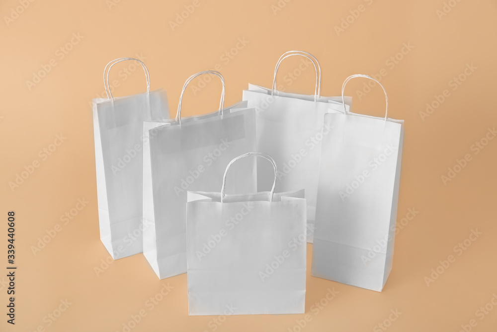 Paper shopping bags on color background