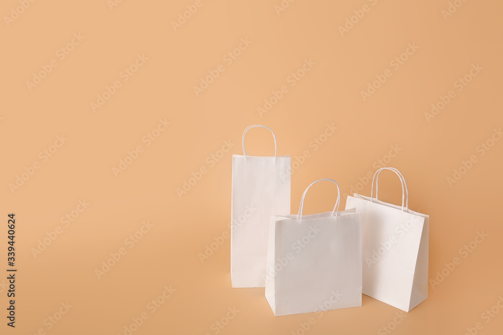 Paper shopping bags on color background