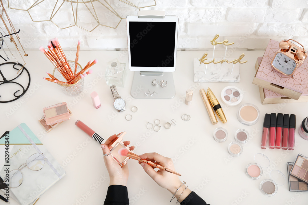 Makeup artist at table with modern tablet computer and cosmetics