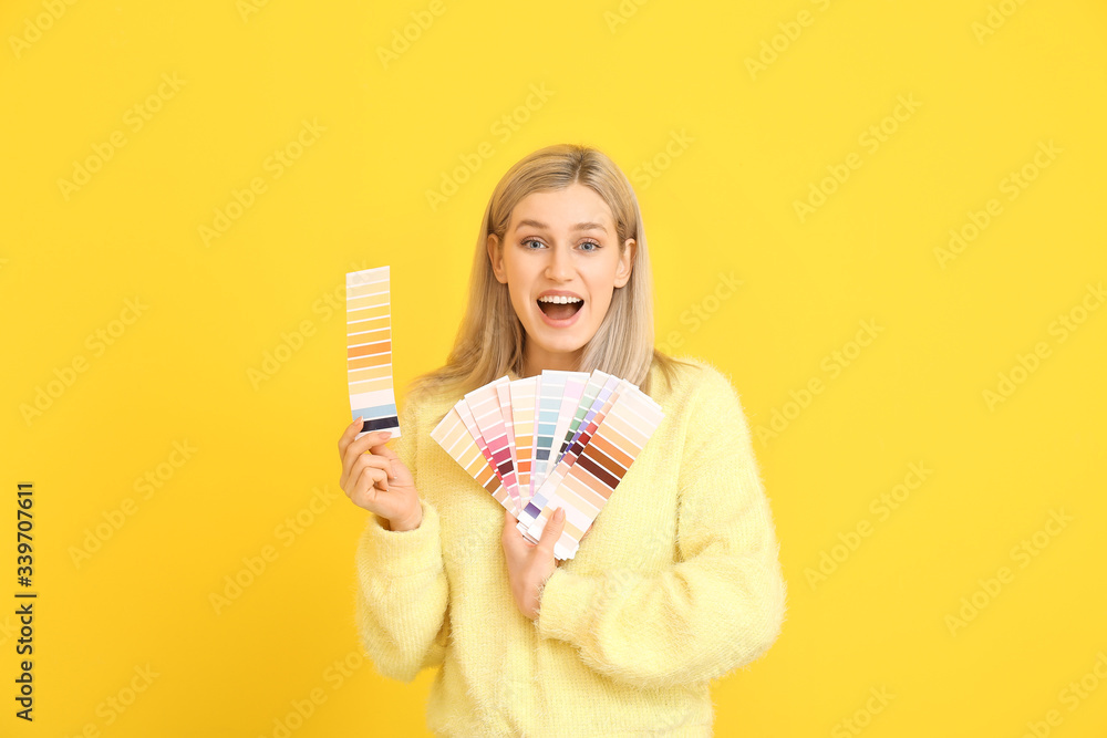 Young woman with paint palette on color background