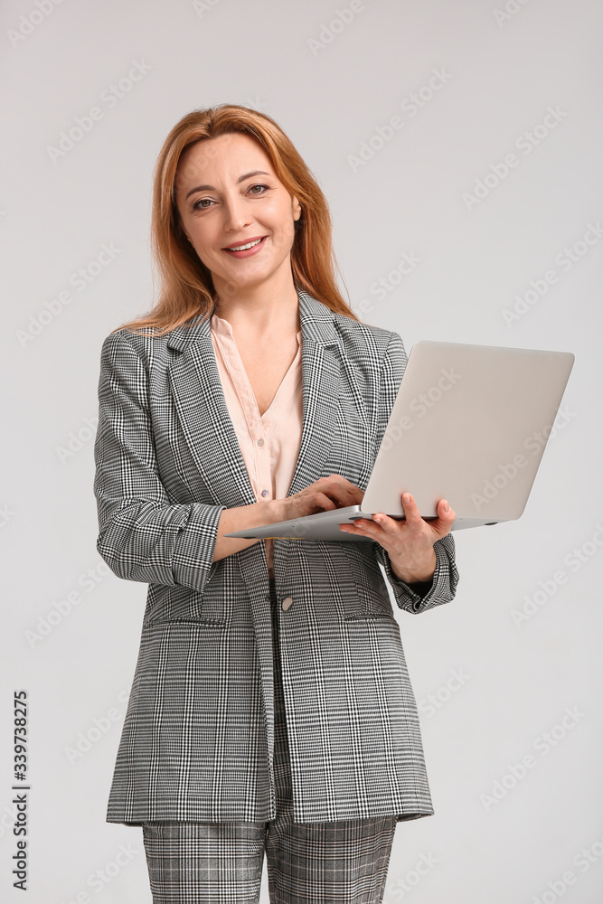 Portrait of stylish businesswoman with laptop on light background