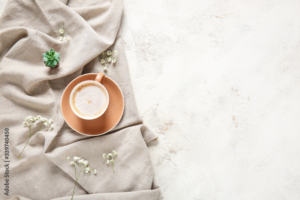 Cup of coffee, plaid and flowers on light background