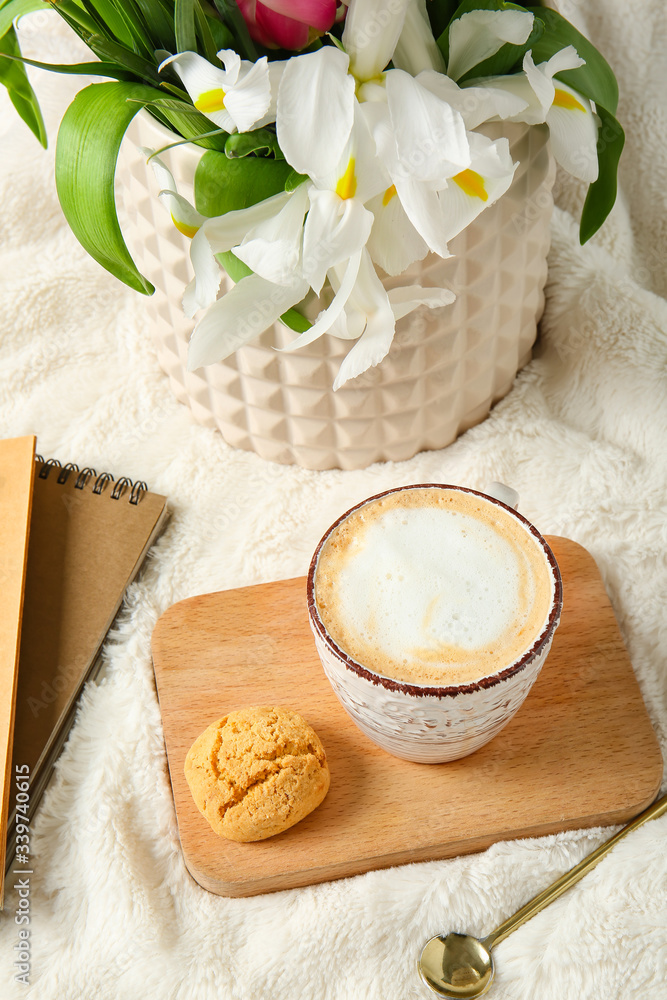 Cup of coffee, flowers and cookie on soft plaid