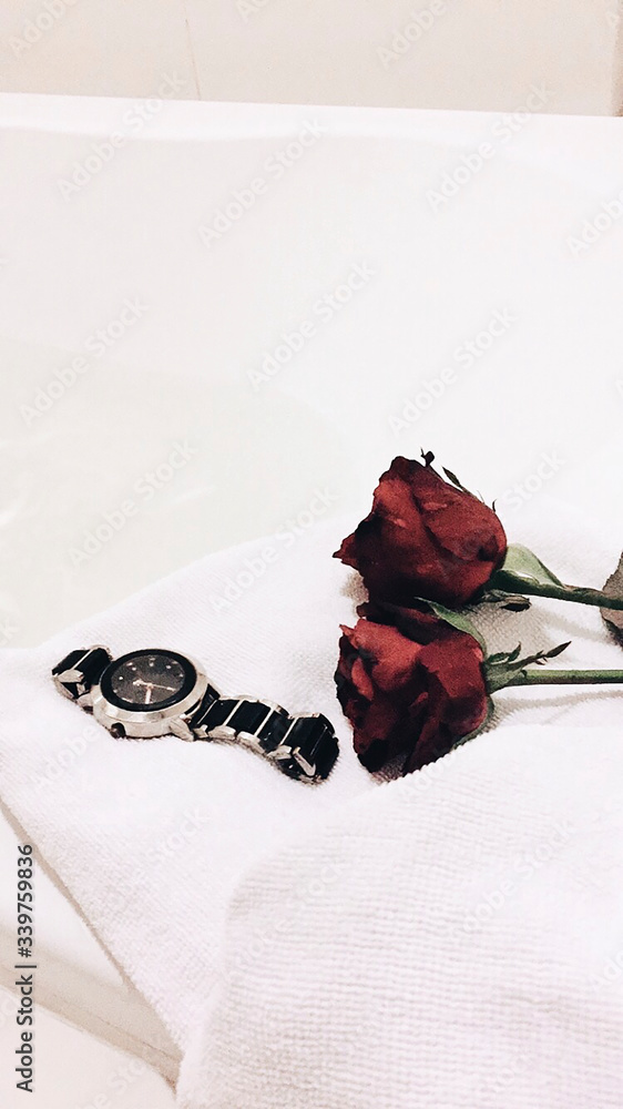 Roses on a bed next to a watch