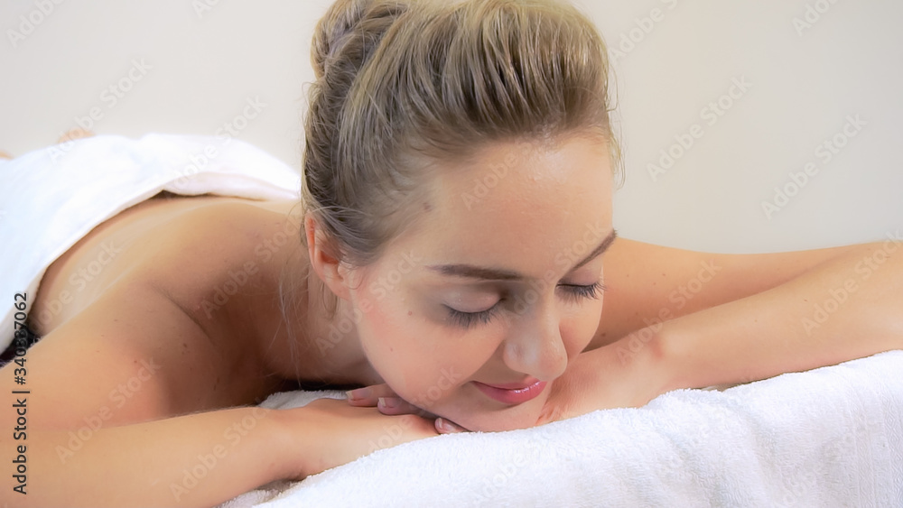 Relaxed woman getting back massage in luxury spa with professional massage therapist. Wellness, heal