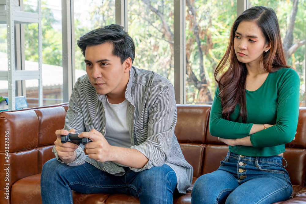 Young Asian couple suffers from computer games addiction. Family problem concept.