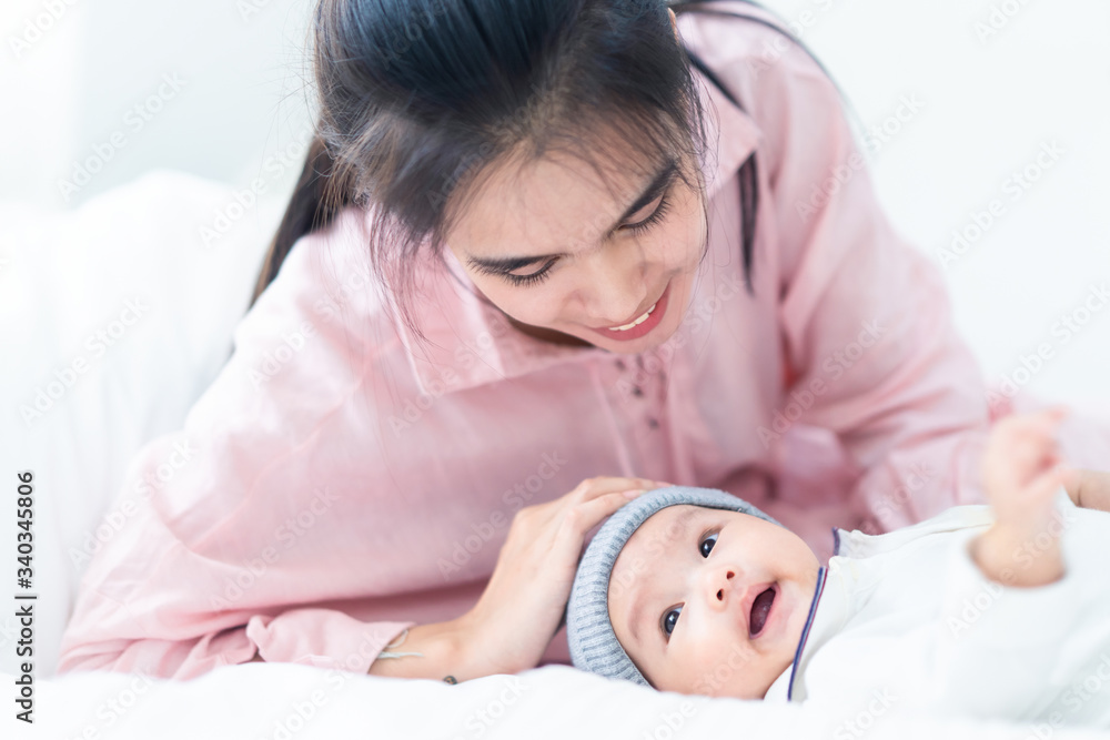 Close up view of beautiful Asian mother and her cheerful lovely newborn baby. Mother holding baby he