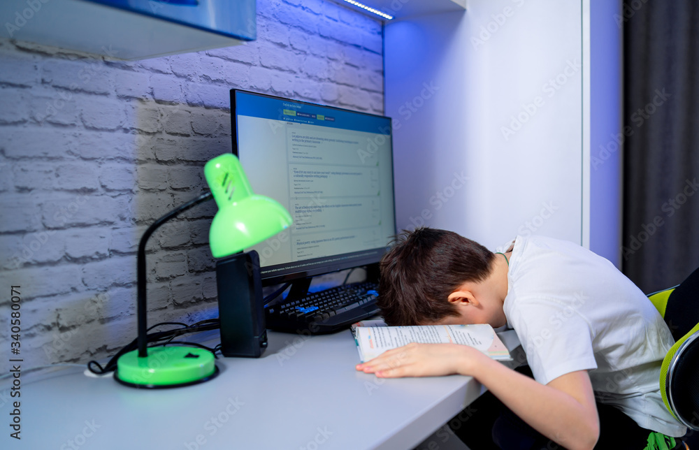 Teenage boy lying himself on the work desk. Taking power nap while studying and preparing for homewo