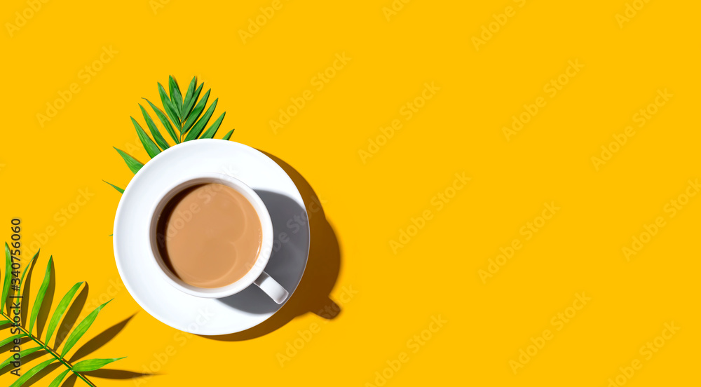 A cup of coffee with tropical leaves - flat lay