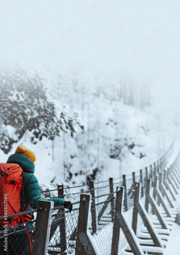 芬兰，一名女子在雪地森林中穿过吊桥