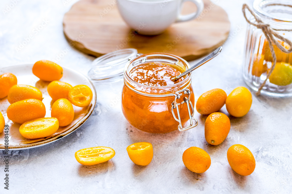 kumquat on plate and jam in jar at gray background