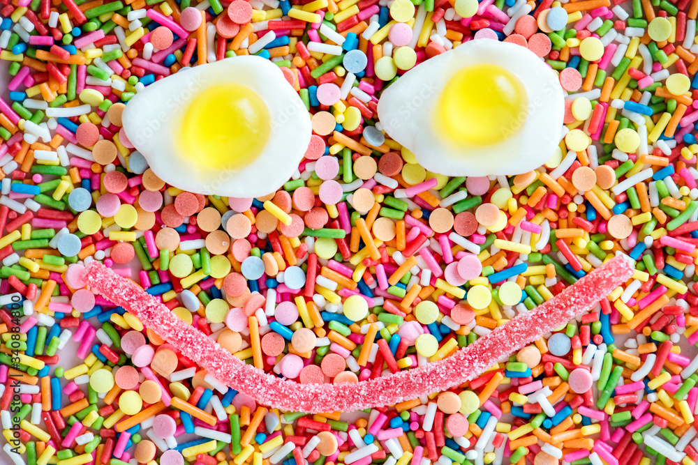 Flatlay of jelly fried eggs forming a smiley face and sprinkles textured background