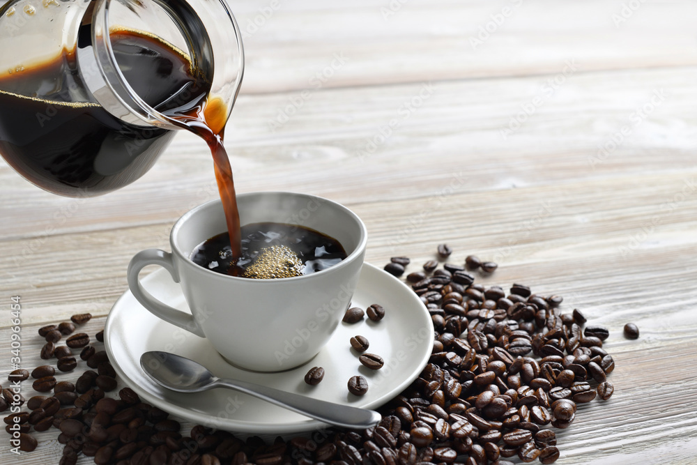 Pouring coffee with smoke on a cup on wooden background