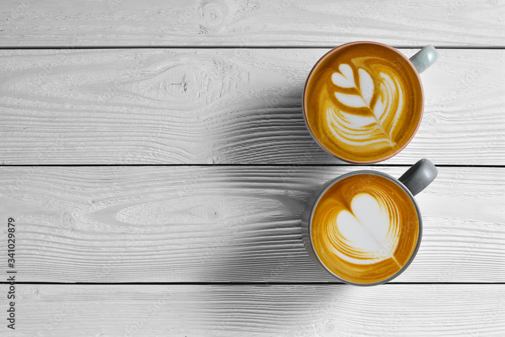 Top view of cups of coffee latte on white wooden background..