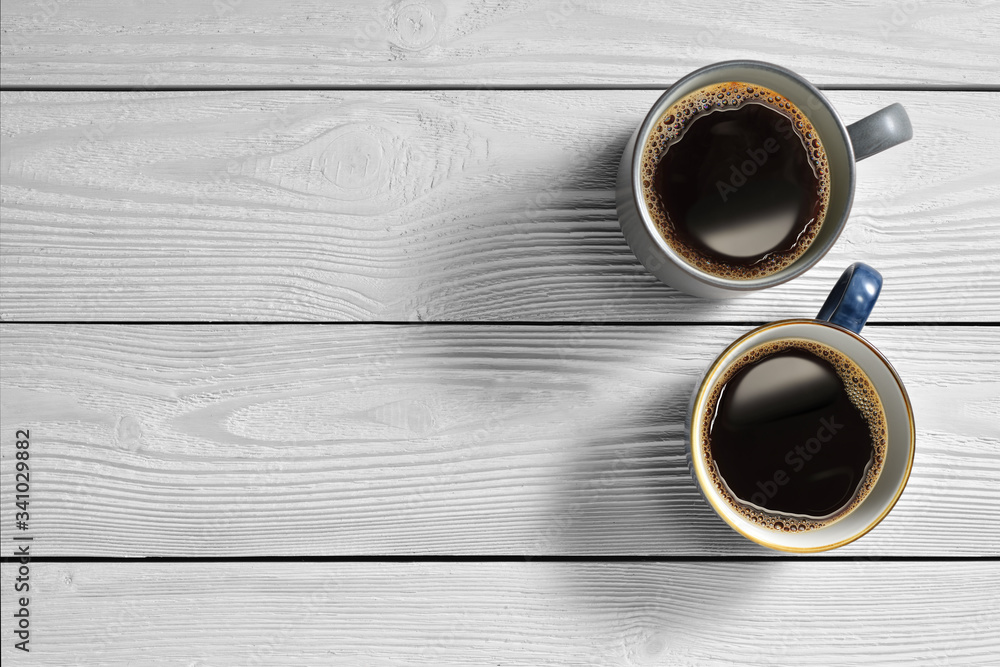 Top view of cups of coffee on white wooden background..