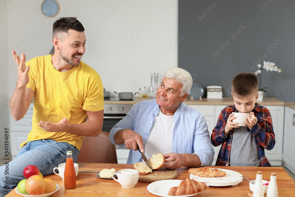 Man with his father and son eating croissants at home