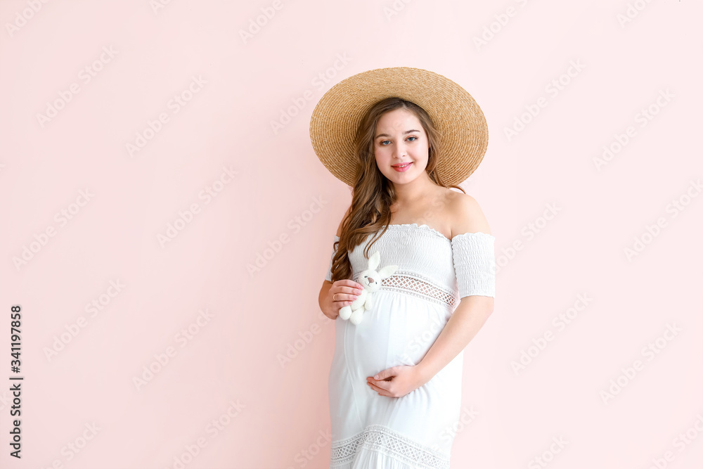 Beautiful pregnant woman with toy on color background