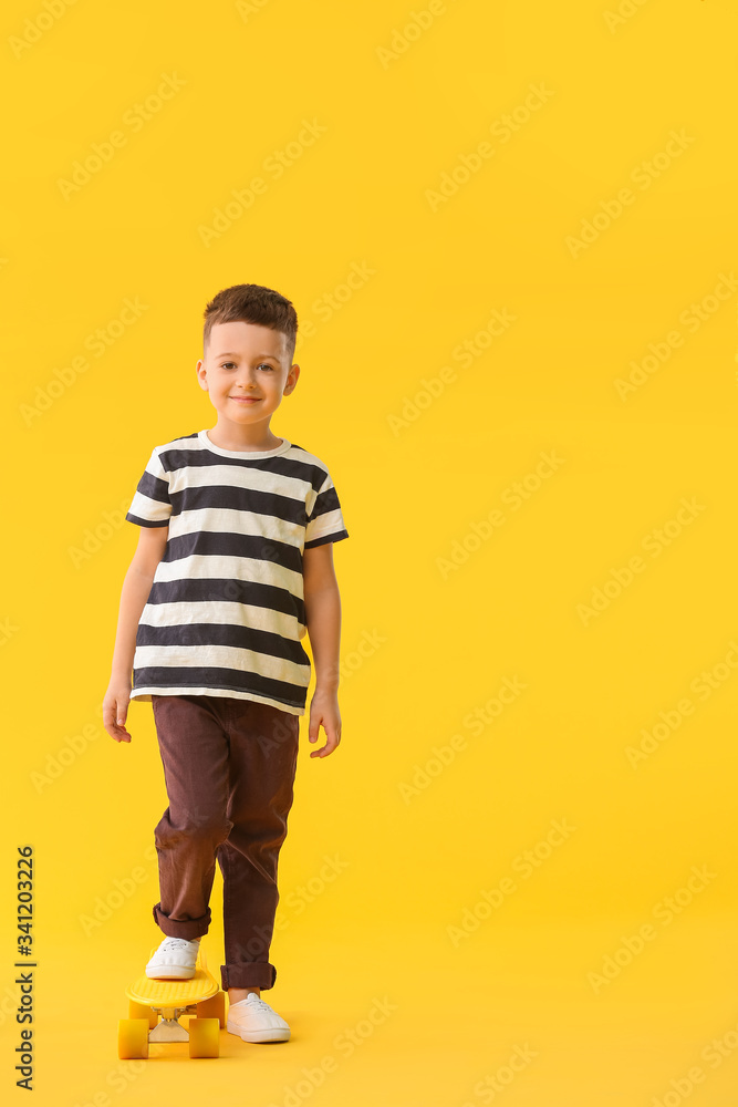 Cute little boy with skateboard on color background