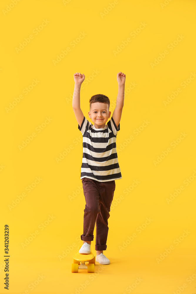 Cute little boy with skateboard on color background