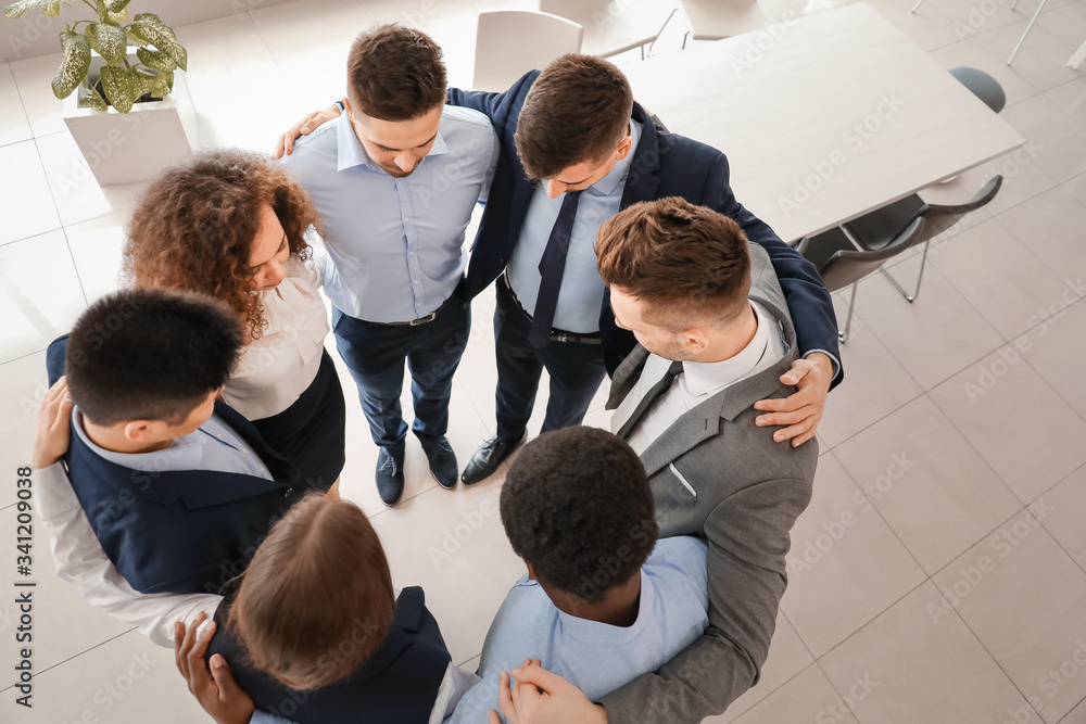 Group of business people hugging in office, top view. Unity concept