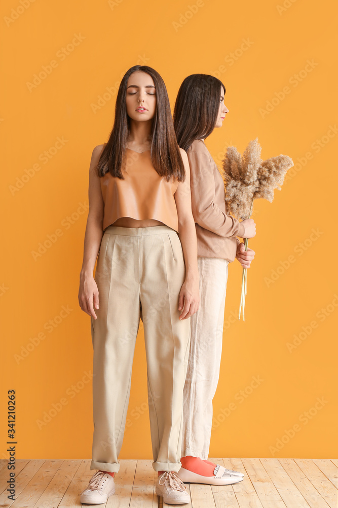 Stylish young women near color wall