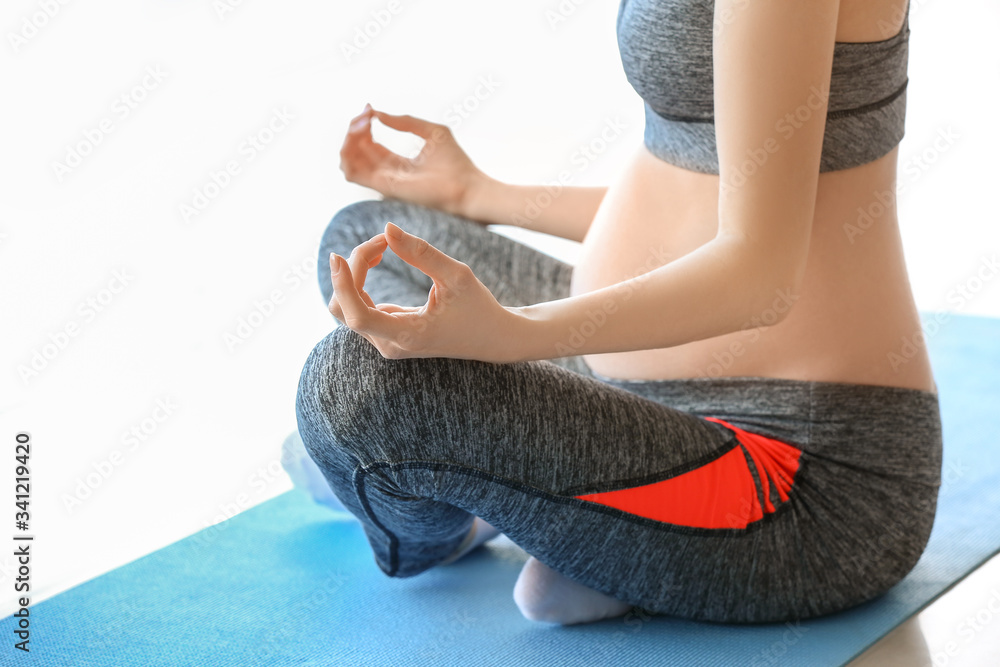 Young pregnant woman practicing yoga in gym