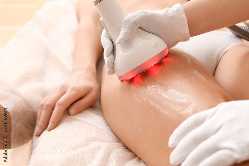 Beautiful woman undergoing procedure of anti-cellulite massage in beauty salon, closeup