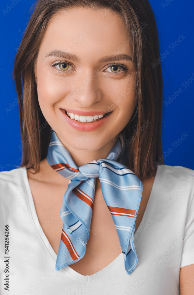 Beautiful young woman with stylish scarf on color background