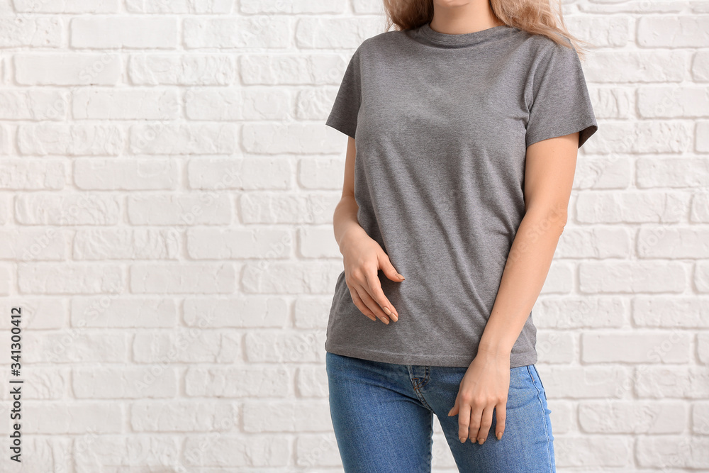 Woman in stylish t-shirt on white brick background