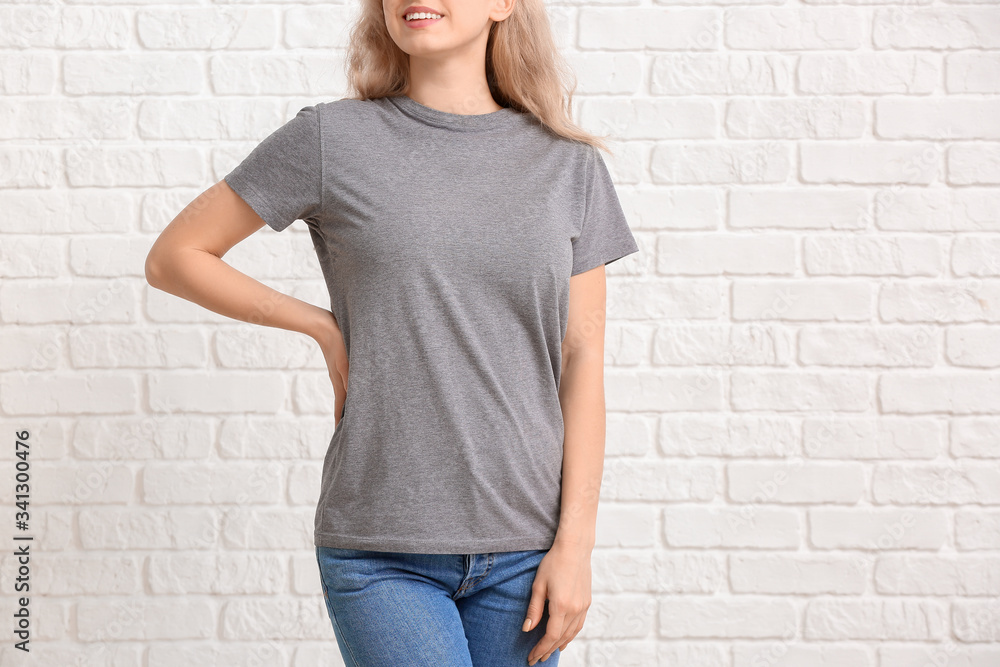 Woman in stylish t-shirt on white brick background