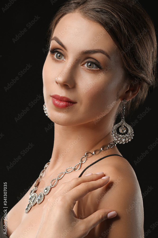 Young woman with beautiful jewellery on dark background