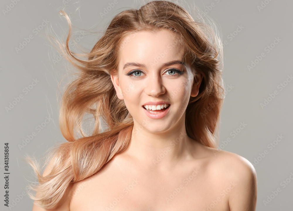 Young blonde with beautiful hair on grey background