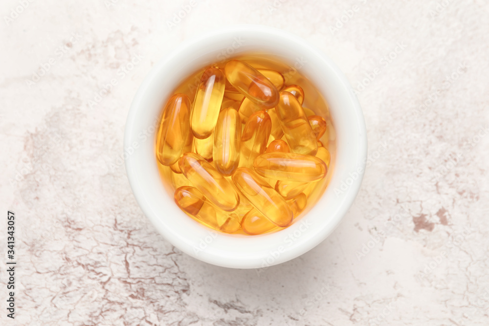 Bowl with fish oil capsules on table