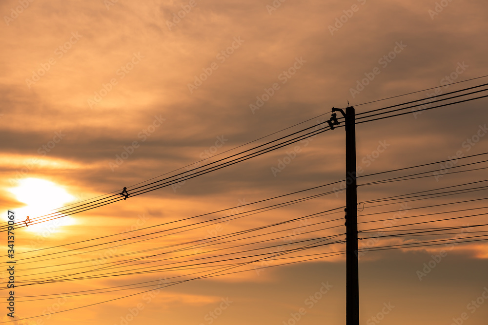 Silhouettes of the power lines and wires in a residential neighborhood back-lit by the evening sky