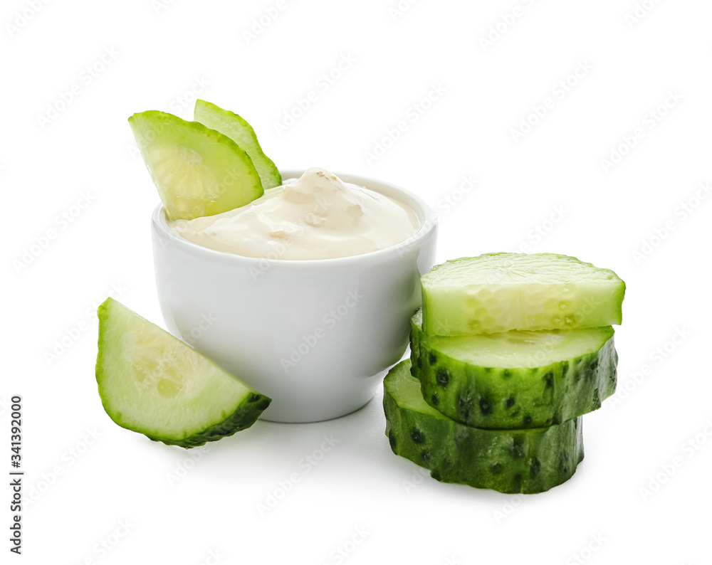 Delicious yogurt sauce with cucumber in bowl on white background