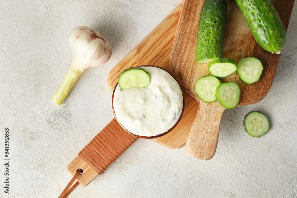 Delicious yogurt sauce with cucumber in bowl on table