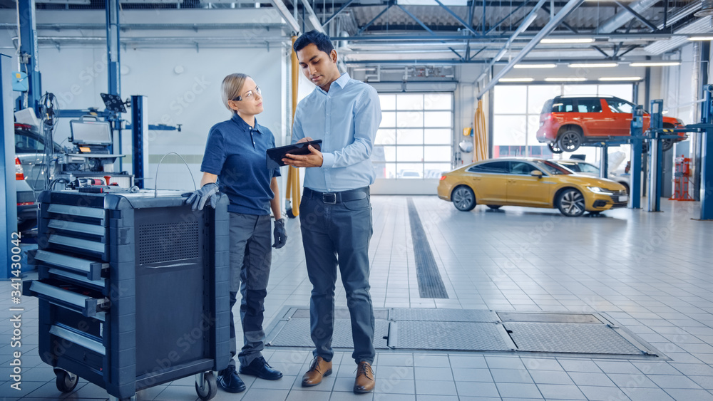 Car Service Manager and a Confident Female Mechanic Talk About Work Related Topics. They Use a Table