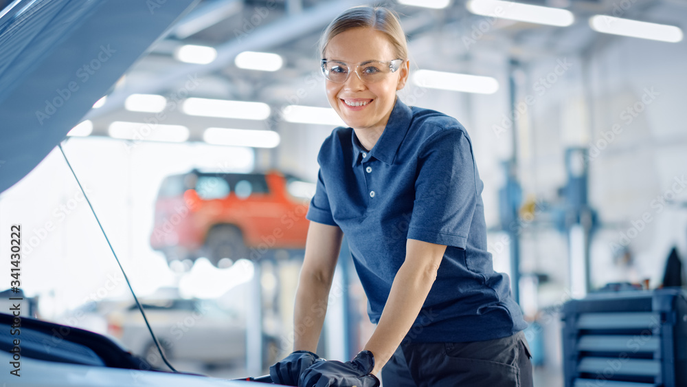 Beautiful Empowering Female Car Mechanic is Working on a Vehicle in a Service. She Looks Happy While