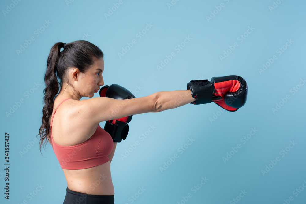 运动型女子在蓝色背景下挥拳