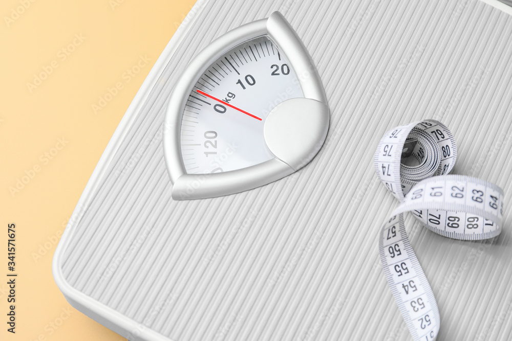 Weight scales with measuring tape on color background, closeup. Slimming concept