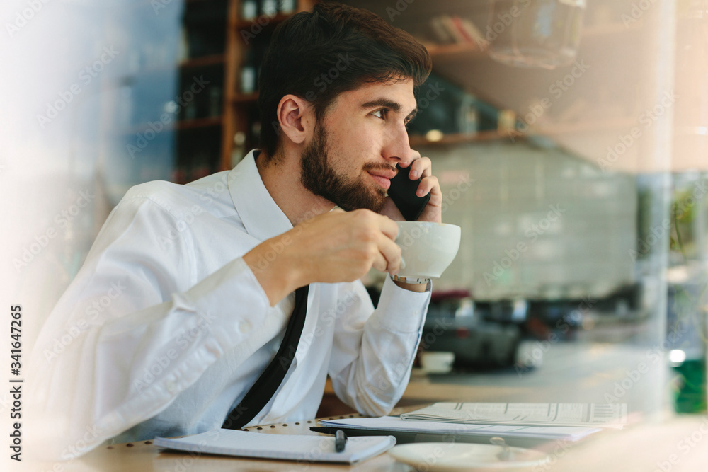 Businessman having coffee and talking on phone at cafe