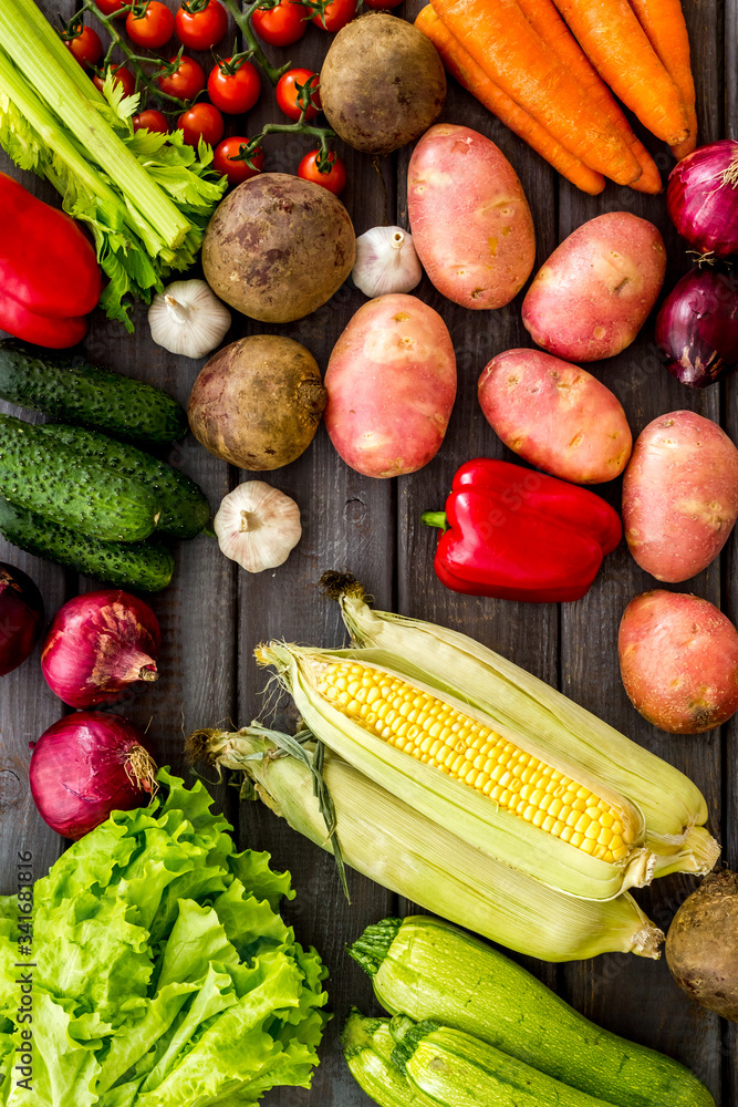 Fresh vegetables still life. Potato, cucumber, beet carrot, greenery on dark wooden background top-d