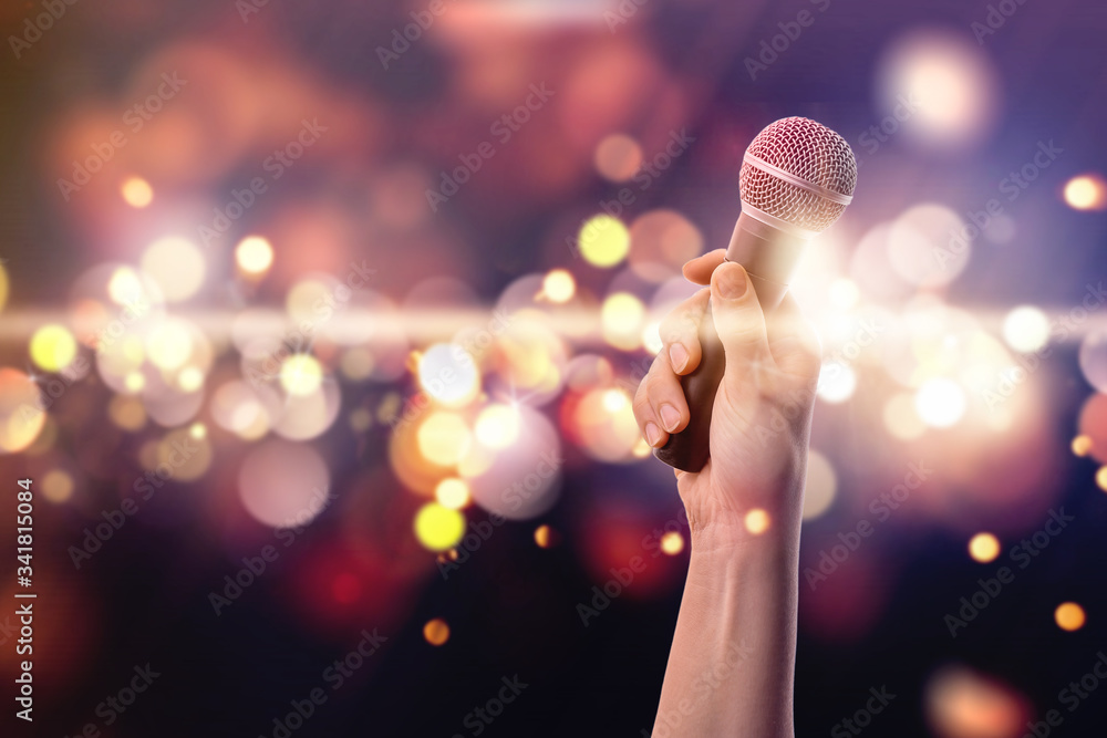 Female hand with microphone against blurred lights