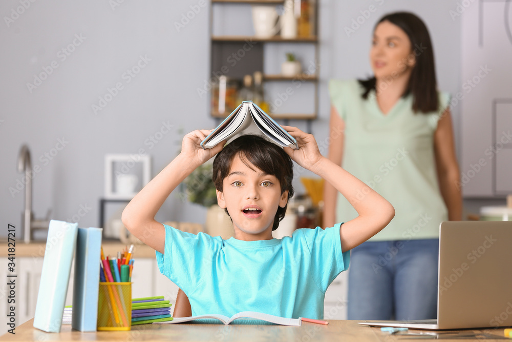 Troubled little boy doing homework in kitchen