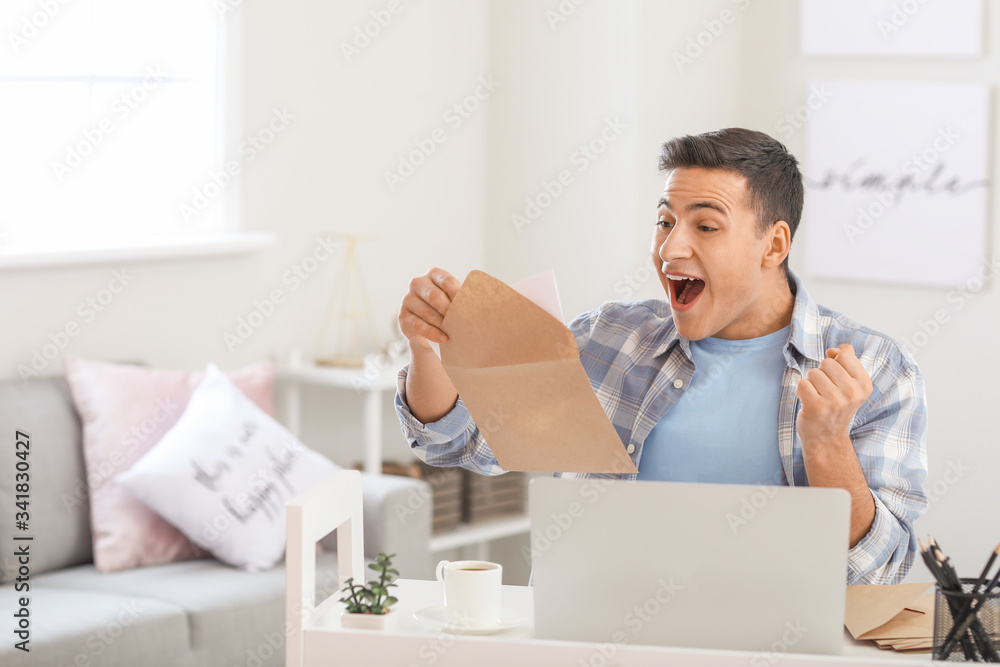 Happy young man with letter at home