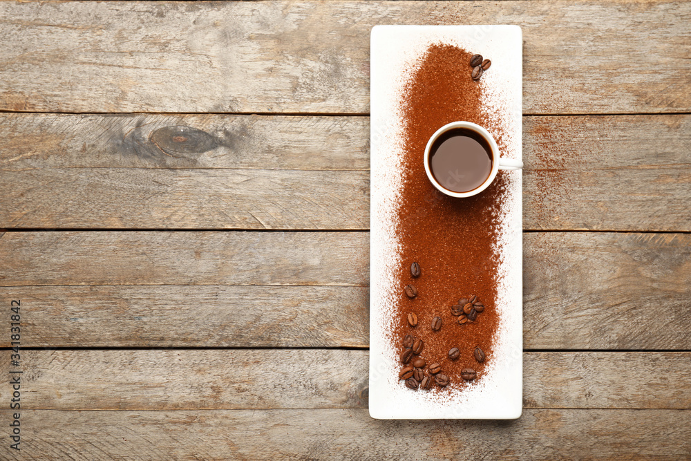 Cup of coffee with powder and plate on wooden background